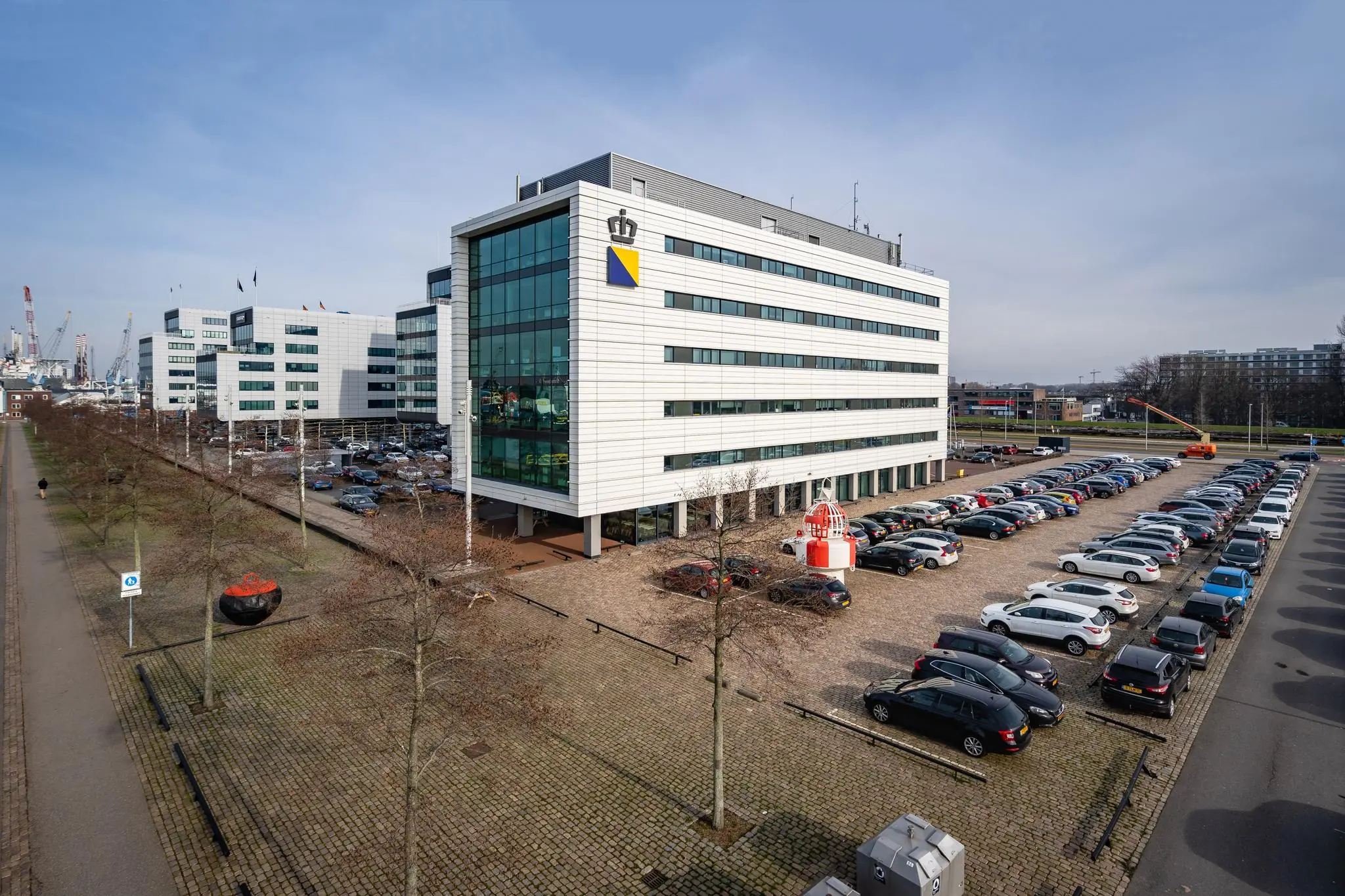 Kantoorgebouw aan de Waalhaven Oostzijde in Rotterdam met een vol parkeertterrein op de voorgrond.